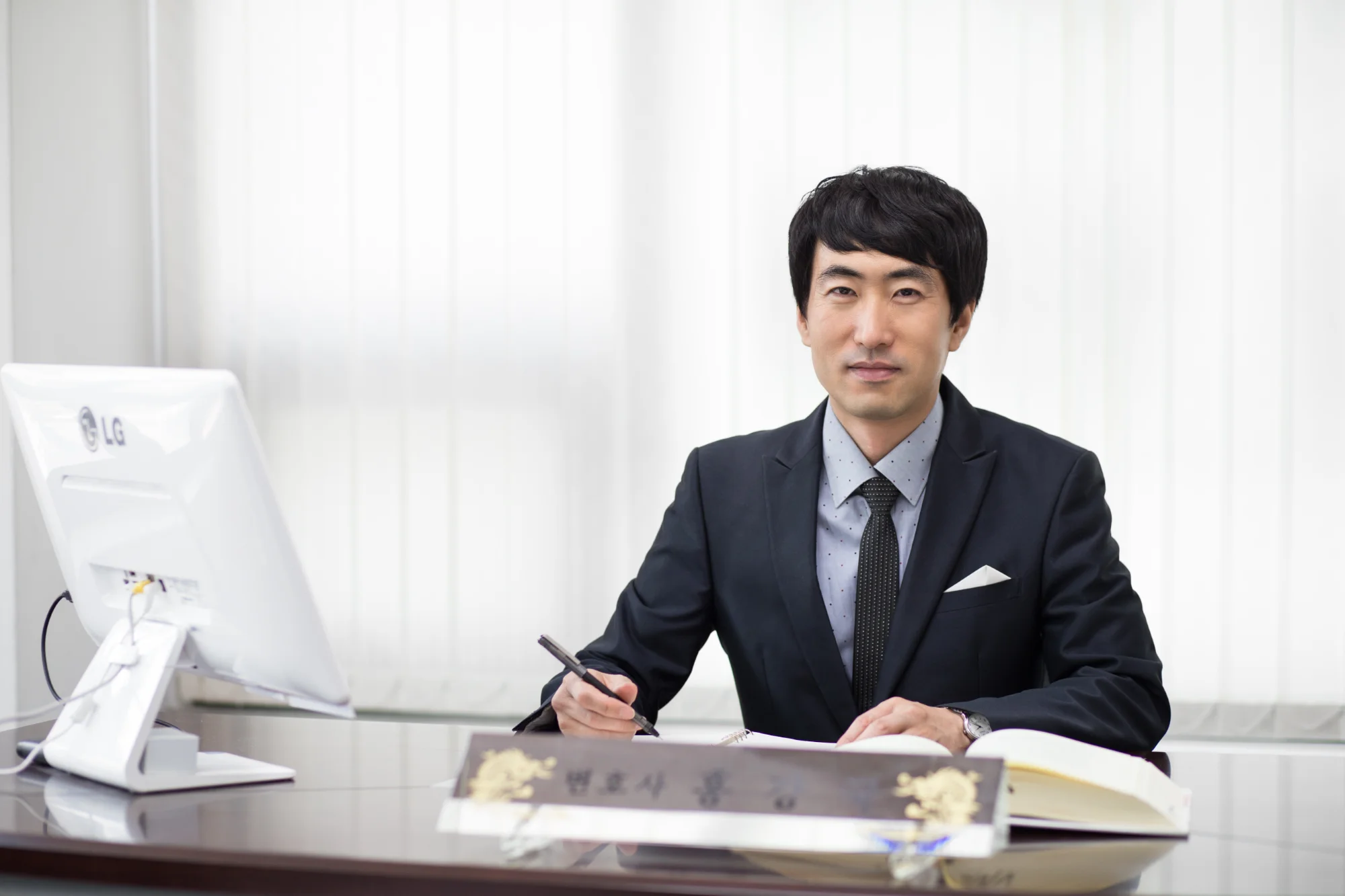 '변호사 홍강국' 명패가 놓인 책상에 앉아 있는 홍강국 대표변호사